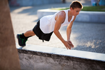 Teenager performing push-ups outdoor in city