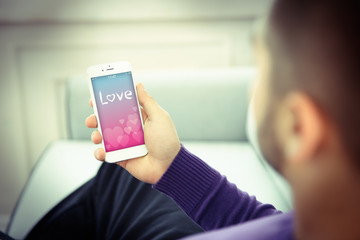 Wall Mural - Young man using his phone with romantic screensaver