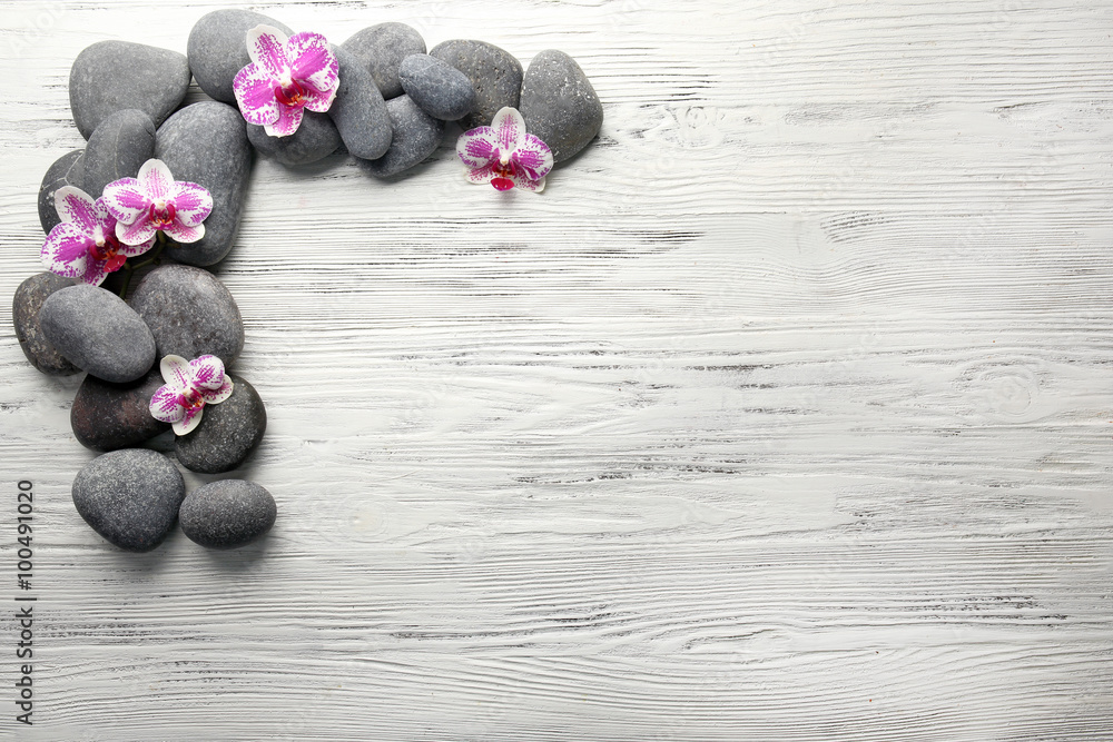 Spa stones and orchids on wooden background