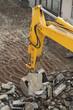 Yellow excavator digs dirt, asphalt and gravel on construction site. Motion blur.