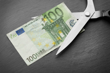 Poster - Concept of spending money - scissors cut money on black background