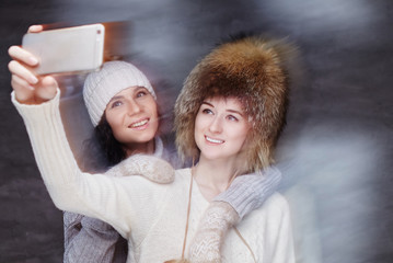 Wall Mural - Two smiling girls in winter fur hats.