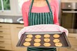 Mid section of woman showing biscuits on baking tin