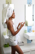© eric - Young african american black lady in bathroom using skin product and taking care of her health.
