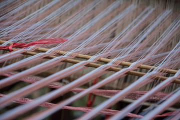 Wall Mural - close up of weaving silk in traditional way at manual loom. Thailand