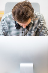 Portrait of young creative with headphone sitting in front of co