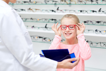 Wall Mural - optician and girl choosing glasses at optics store