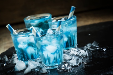 Blue cocktail with crushed ice on a dark background, selective f