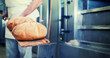 Bäcker mit Brot in Bäckerei auf Schaufel steht vor dem Backofen