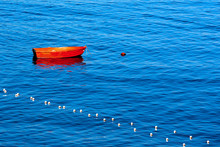 Red Row Boat Moored To Buoy / Red Rowing Boat Moored In A Harbor To A Red Buoy On The Blue Waves