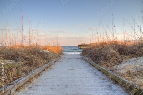 Atlantic Ocean Background. Boardwalk through dune grass to the Atlantic Ocean with a pier in the background. Myrtle Beach, South Carolina. 