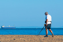 Man Uses Metal Detector On A Beach