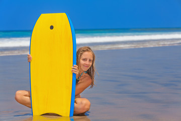 Happy girl - young surfer with bodyboard has fun on sea sand beach with waves. Family lifestyle, people water sport lessons, swimming activity on summer surf camp vacation with child in ocean island.