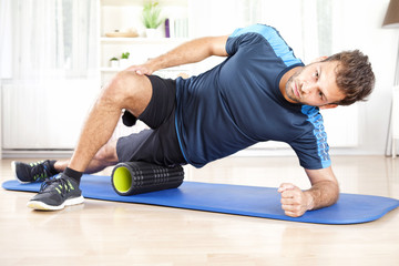 Athletic Man in Side Planking Using Foam Roller