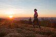 young woman running on the trail in the morning with sunrise and sun flares