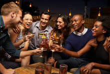 Group Of Friends Enjoying Night Out At Rooftop Bar