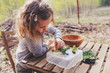 child girl exploring nature in early spring, looking at first sprouts with loupe. Teaching kids to love nature.
