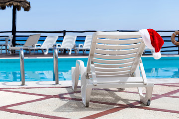 Wall Mural - Santa Helper Hat on Lounge sunbed near swimming pool