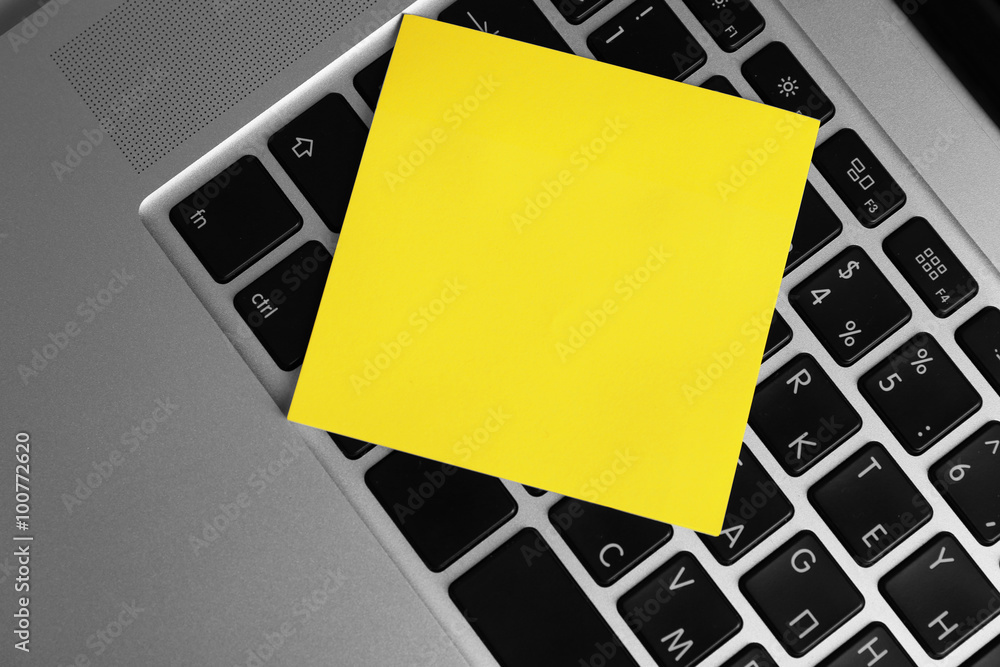 Empty yellow adhesive paper on laptop keyboard, on light background