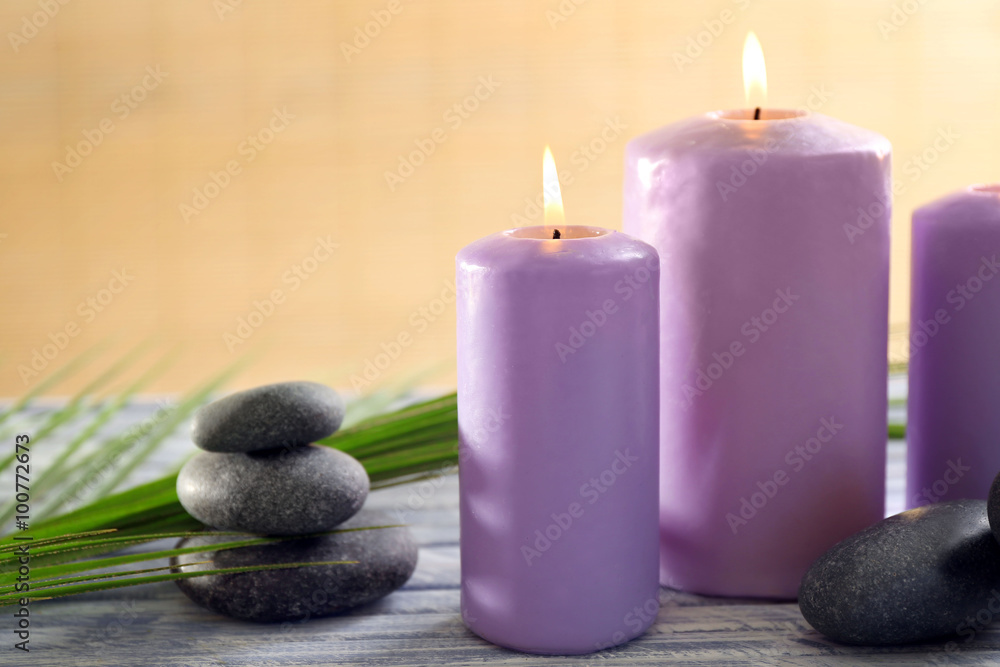 Purple candles with spa stones and bamboo on table