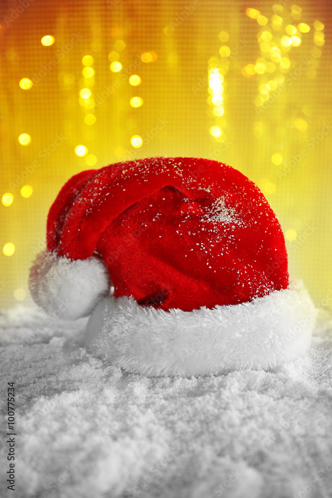 Santa Claus hat on a snowy table over glitter background