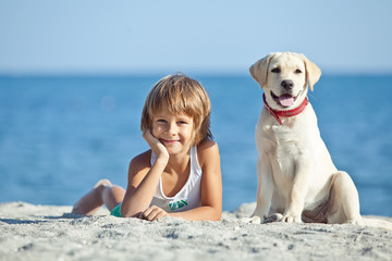 Happy kid with a dog on the beach 