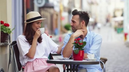 Canvas Print - Happy couple talking at outdoors cafe drinking coffee and hugging
