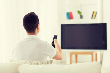 Wall Mural - man watching tv and changing channels at home