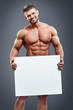 © kegfire - Muscular young man holding blank white poster