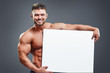 © kegfire - Smiling bodybuilder holding blank white poster