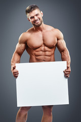 muscular young man holding blank white poster