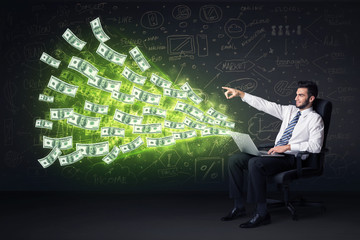 Canvas Print - Businessman sitting in chair holding laptop with dollar bills co