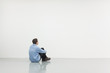 Man sitting in front of a white wall