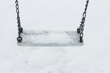 Empty Swing With Snow On It In The Winter Season