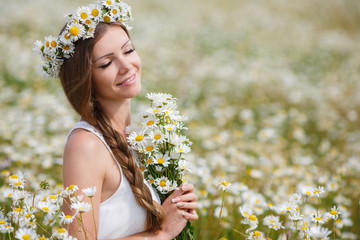 Wall Mural - Beautiful young woman in a field of blooming daisies