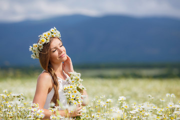 Wall Mural - Beautiful young woman in a field of blooming daisies