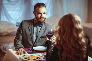 Wall Mural - Beautiful young couple with glasses of red wine in luxury restaurant