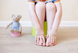 closeup of legs of the child sitting on the potty. the idea of training the child to the potty with a toy bear, which also sits on a toy potty