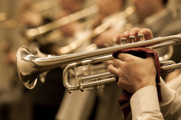  The trumpet in the hands of a musician in the orchestra closeup