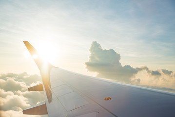 Wing of airplane on cloud sky from window in morning.