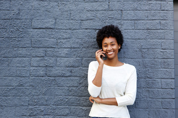 Wall Mural - Happy african woman using mobile phone and smiling