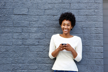 Wall Mural - Smiling young african woman with mobile phone