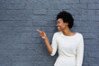 © mimagephotos - Happy young african woman pointing at copy space