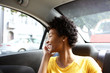 © mimagephotos - Happy african woman in a car talking on cellphone