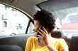 © mimagephotos - African woman on back seat of car making a phone call