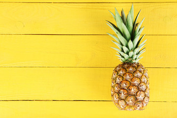 Wall Mural - Ripe pineapple on a yellow wooden background