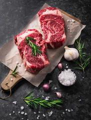 Wall Mural - Two raw fresh marbled meat black angus steak ribeye, garlic, salt and  on dark background