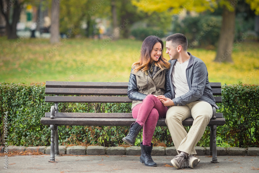 Happy young couple in love sitting on a park bench Stock Photo | Adobe ...