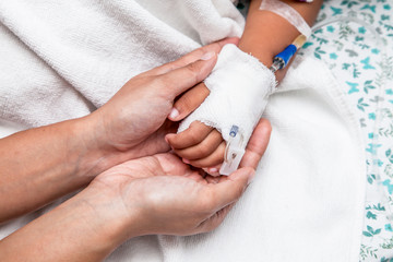 mother holding child's hand who have IV solution in the hospital