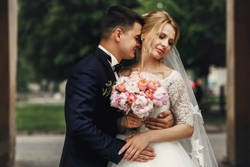 Wall Mural - Happy sensual handsome groom and blonde beautiful bride in white